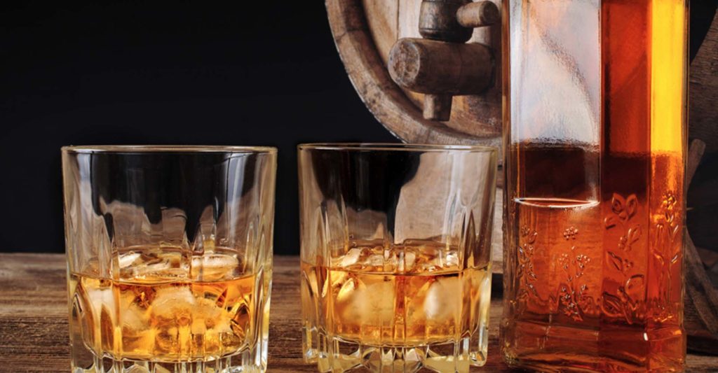 Two whisky glasses, a bottle of whisky and a whisky barrel