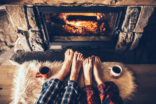 A couple warming their feet by the fire