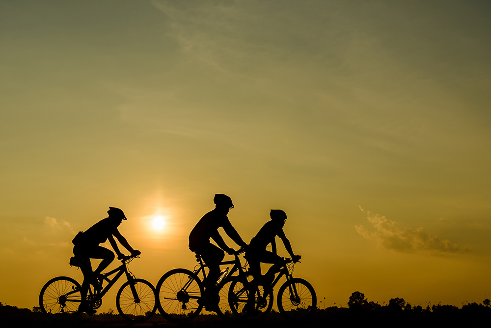 Three cyclists at sunset.