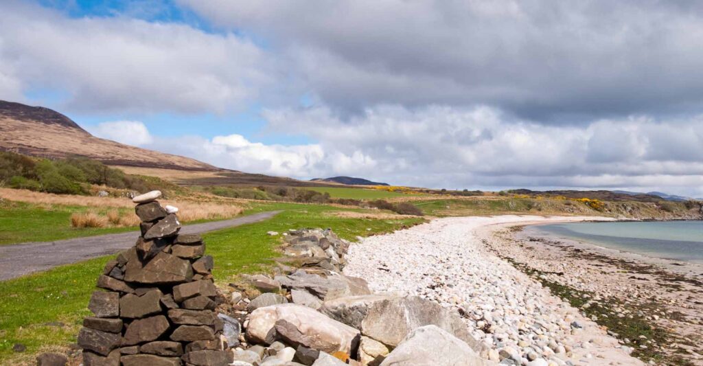 A road by a white beach on Islay on a sunny day.