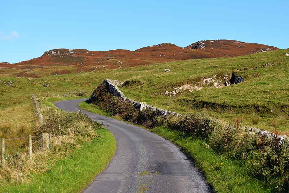 A winding road through Islay hills on a blue sky day.